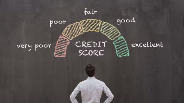 Person reviewing credit score report on laptop with calculator