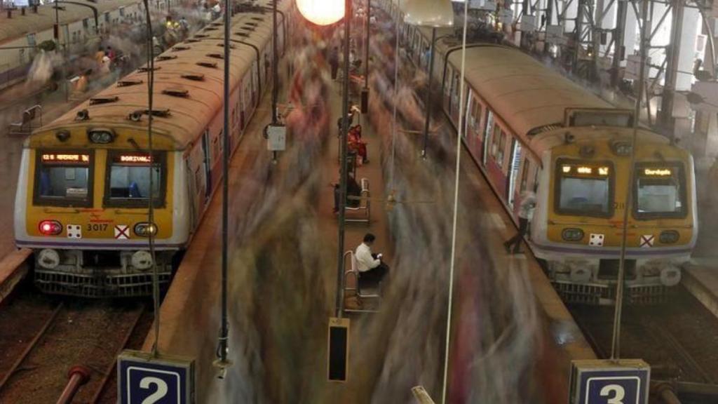 Indian Railways passengers boarding a train with updated fare signage at the station.