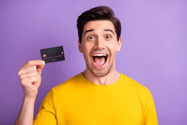 A person holding their first credit card with excitement