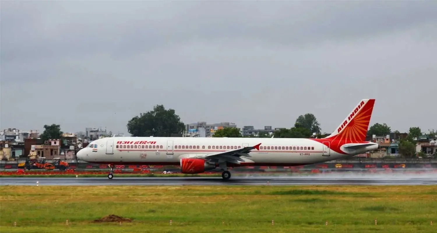Air India plane grounded on runway with engineers inspecting aircraft wing.