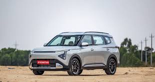 Kia Carens Clavis EV front and side profile with futuristic LED lights and city backdrop