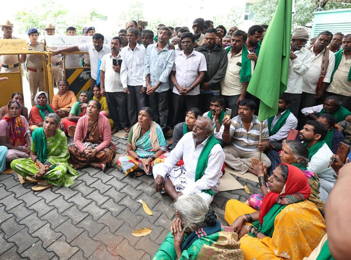 Farmers protesting land acquisition in Devanahalli with banners and slogans.