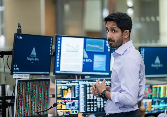 Young finance professional in blazer analyzing stock charts with coffee and Vizzve Finacr dashboard open on screen