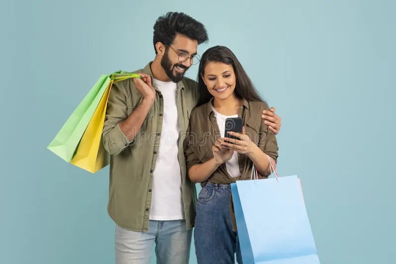 Smiling Indian couple holding travel bags and wallet