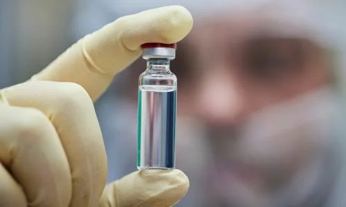 Doctor holding a COVID-19 vaccine vial with a "Myth Busted" sign