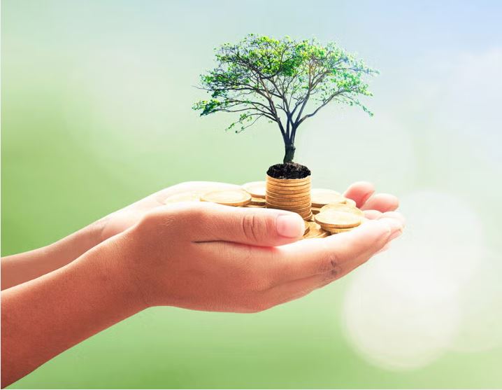 A finance professional shaking hands with a social worker, with charts and a community board in the background—symbolizing finance with social good