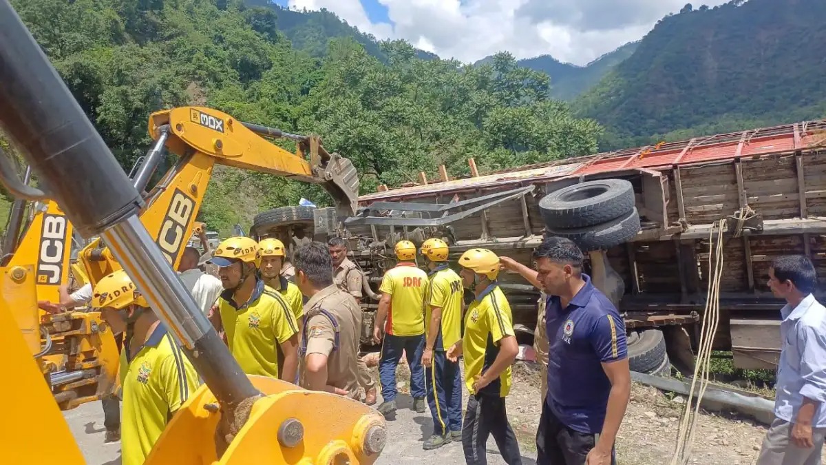 Overturned truck on a mountainous road in Uttarakhand with police and ambulance on site