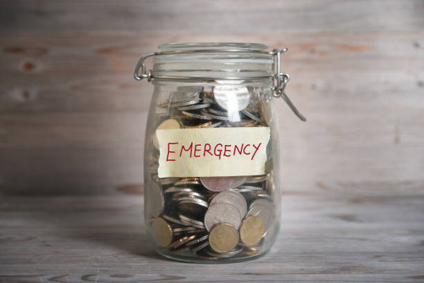 A young professional placing small coins into a labeled "Emergency Fund" jar, with the Vizzve logo in the background.