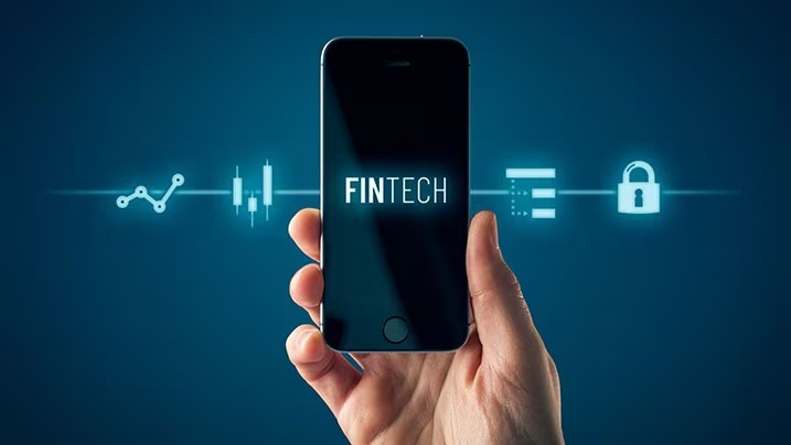 Young Indian using a mobile fintech app with traditional bank building in background