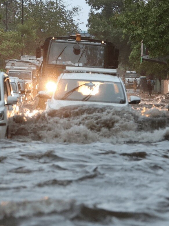 Flooded city street with stranded vehicles and people walking in water, symbolizing urban disaster and financial unpreparedness