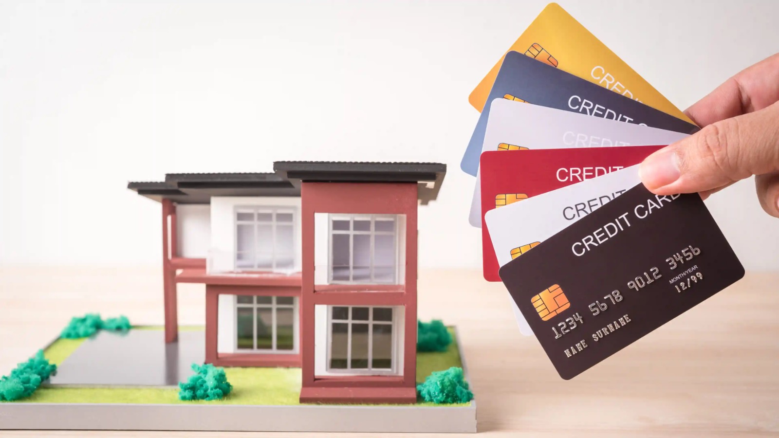 Young professional using credit card to pay rent through mobile app with calculator and bills on desk