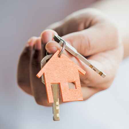 Happy Indian family in front of their new home with loan documents and house keys