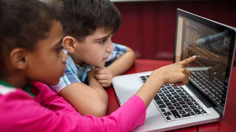 A young child coding on a tablet with colorful blocks and logic puzzles