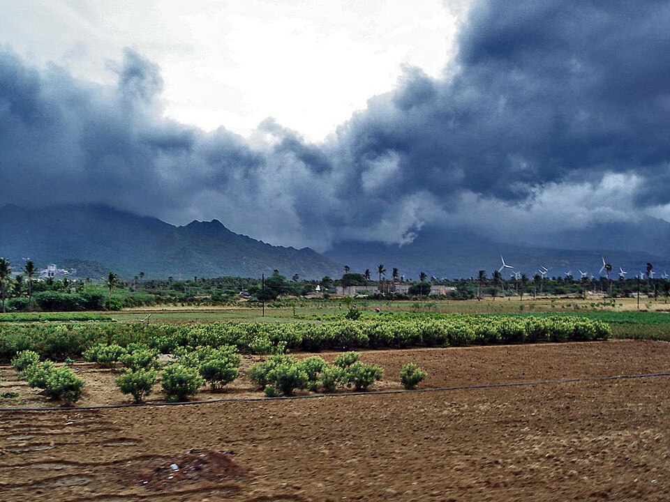 Monsoon clouds over Indian farmland and urban skyline