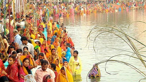 Devotees offering Arghya to the setting sun during Chhath Puja standing in a river
