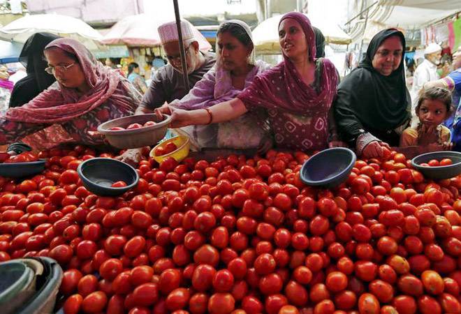 A farmer sitting beside crates of tomatoes at a mandi, looking disappointed