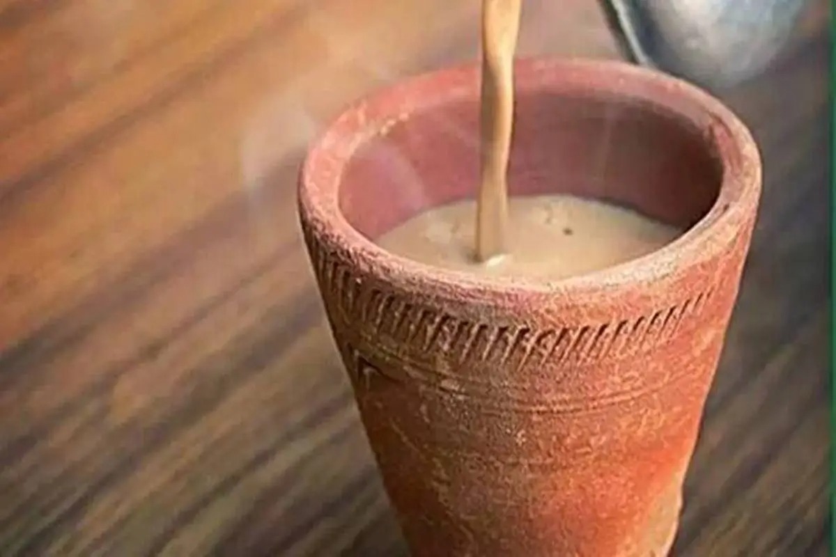 A chaiwala pouring hot tea into clay cups on a moving Indian train