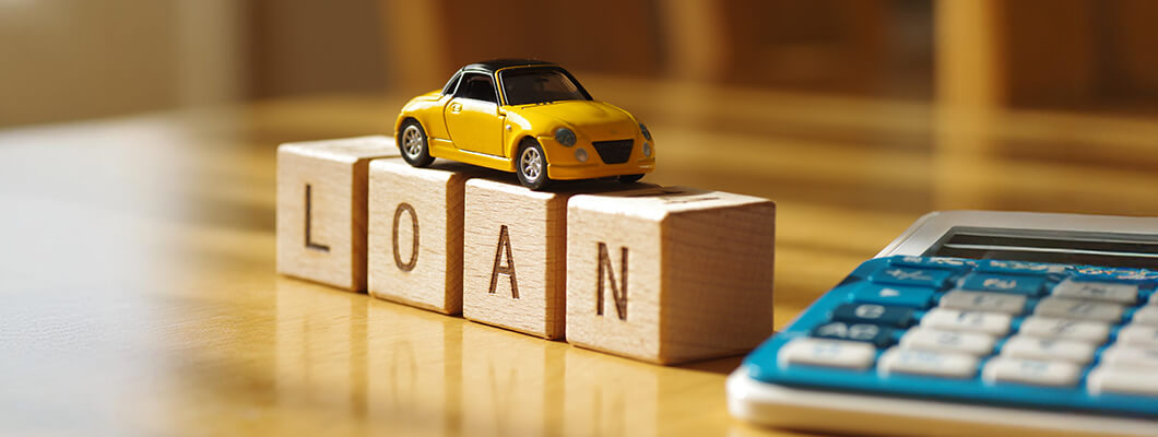 Person signing car loan documents with car and calculator in background
