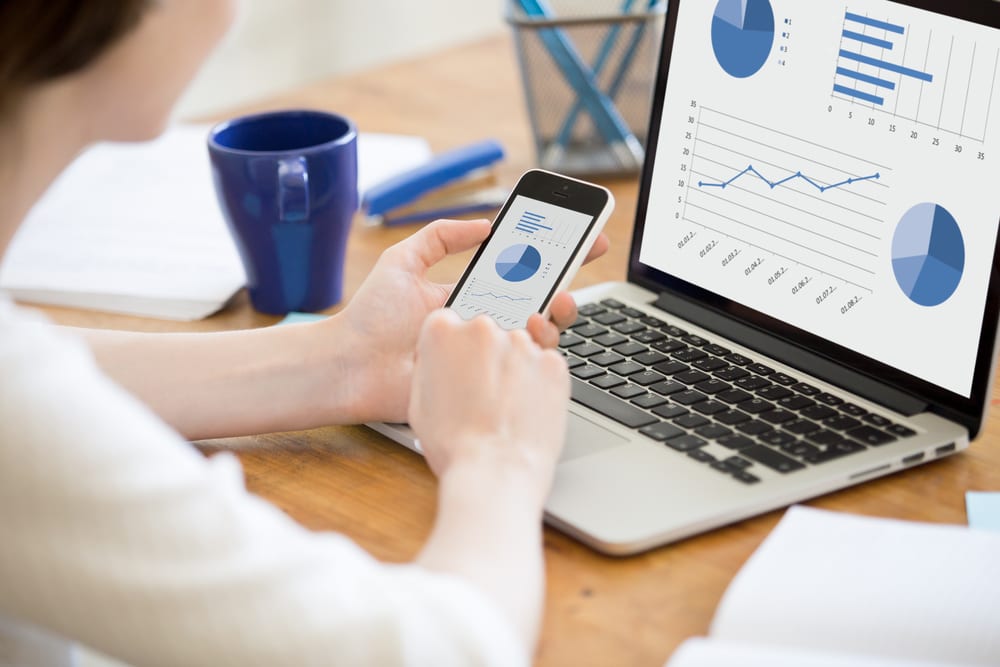 Young professional tracking finances on laptop and mobile app