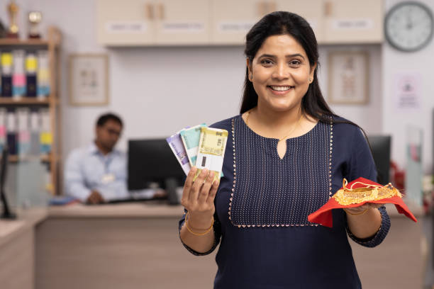 Indian woman holding gold jewelry while signing a loan form, symbolizing trust in gold loans over banks.