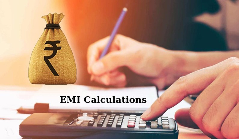 Person calculating monthly EMIs with a calculator and loan documents on a desk.