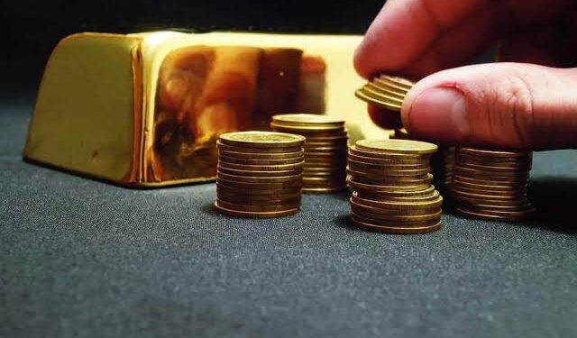 Gold bars and coins with price tags showing record high gold rates in India.