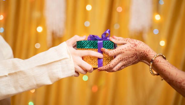 Indian couple receiving wedding gifts with currency notes and gold jewelry.