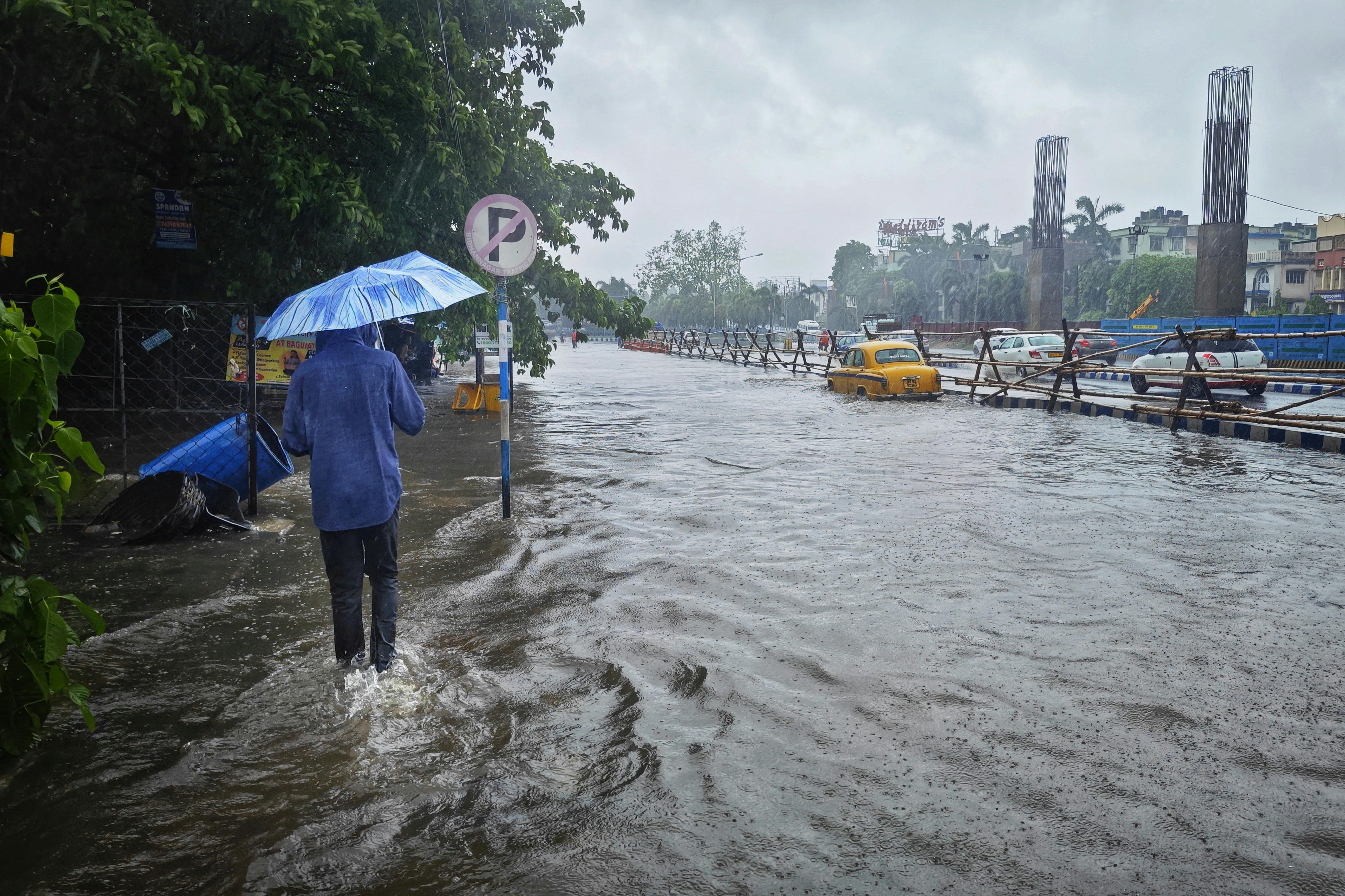 People walking under umbrellas on a flooded street in Karnataka during heavy rainfall