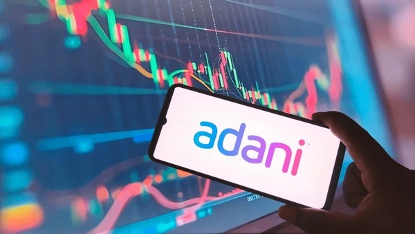 Adani Group buildings with stock market charts in background