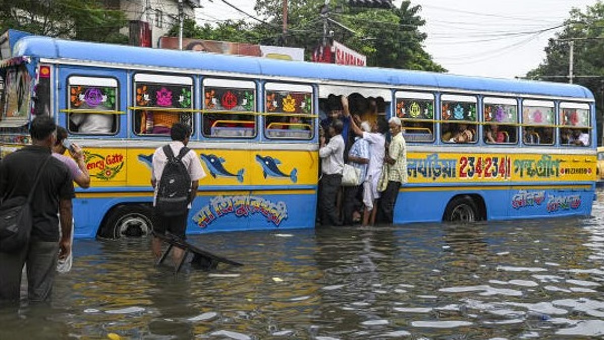 Flooded street in Kolkata with pedestrians during heavy rains before Durga Puja