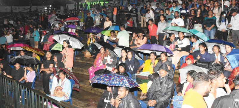 Rain-soaked Dussehra celebration with people holding umbrellas