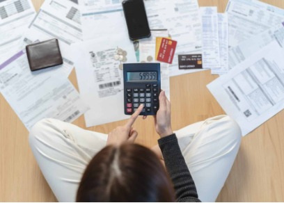 A person using a calculator to plan repayment of credit card debt using a personal loan.