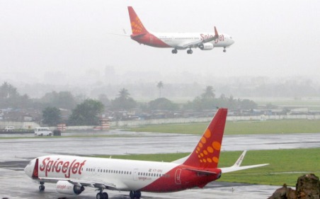 SpiceJet airplane at Delhi airport during heavy rainfall, passengers checking flight updates