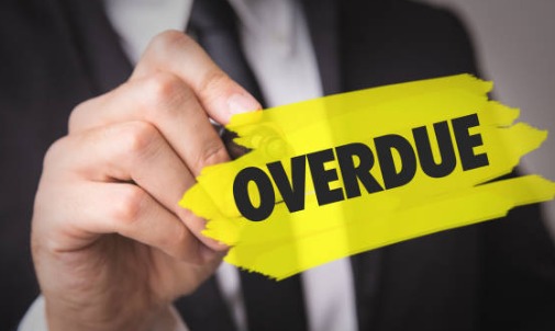 Person reviewing overdue loan notice with calculator on table