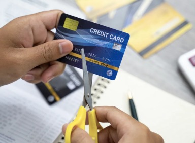 Person cutting a credit card to manage debt