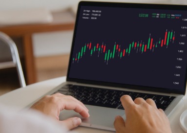 Trader analyzing stock charts on laptop with trading graphs and strategy notes.