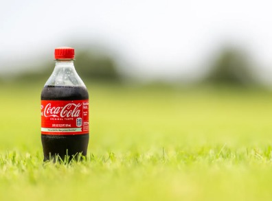 Coca-Cola bottles with stock market graphics, representing the potential IPO of its Indian bottling unit.