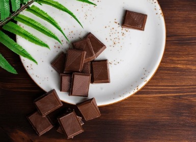 Piece of dark chocolate on a plate with night-time background