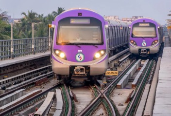 Kolkata Metro train approaching a station with commuters scanning QR codes on mobile apps.