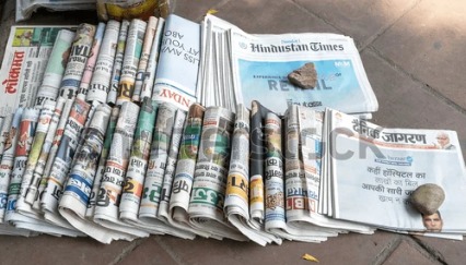 Stacks of Indian newspapers on a vendor’s stand.