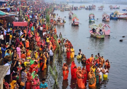 Devotees gathering at a Delhi ghat during Chhath Puja; traffic diversion board in foreground.