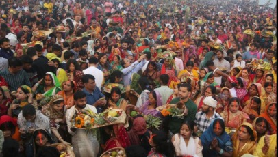 Devotees offering Usha Arghya to the rising Sun during Chhath Puja at a riverbank.