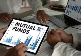 Investor reviewing mutual fund brochures and NFO details on a desk with financial charts and calculator