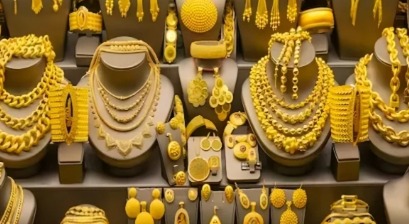 Gold jewellery and coins displayed at an Indian jewellery store showing 18K, 22K, and 24K gold varieties with October 31 price tags.