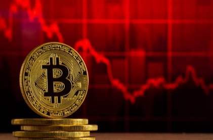Bitcoin symbol and charts showing steep decline after record high slump