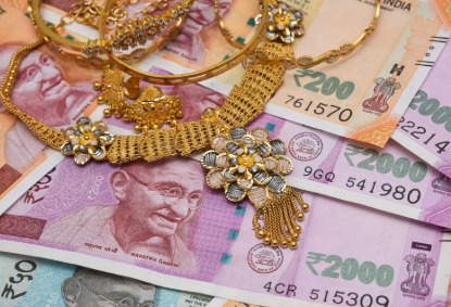 Gold jewelry and Indian rupee notes placed beside a bank loan document representing secured lending growth in India.
