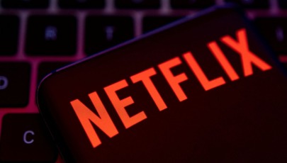 Person watching Netflix on a laptop while analyzing credit score — representing how streaming habits could influence loan eligibility.