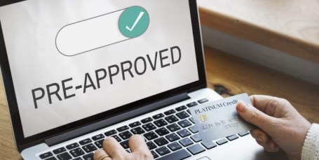 A person reading a pre-approved loan offer on a smartphone with a magnifying glass symbolizing hidden financial terms.