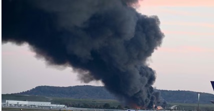 Emergency responders at Kentucky cargo plane crash site after engine falls off mid-air; wreckage scattered across field.