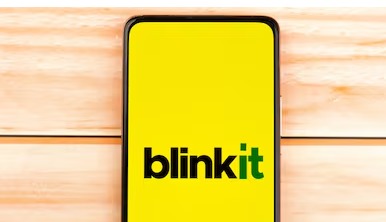 Smartphone screen showing Blinkit app with shopping cart and grocery delivery background.